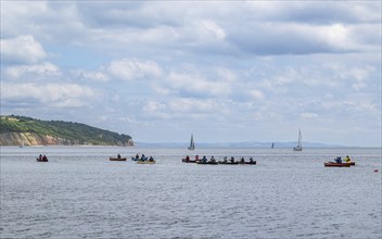 People in a canoe on Seaton Bay with the Haven Cliffs Naturist Beach in the background, Jurassic