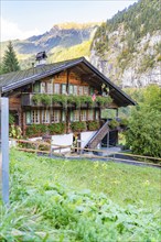 Cosy chalet with lush flowers, traditional Swiss architecture, nestled in a picturesque mountain