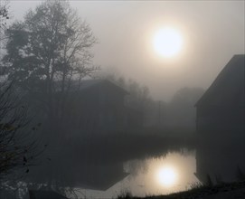 The sun is reflected in the morning mist in the village pond, Othenstorf, Mecklenburg-Vorpommern,