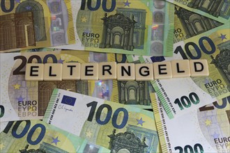 Symbolic image of parental allowance: Letters on euro notes show the word parental allowance