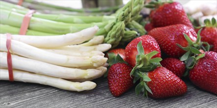 Green asparagus, white asparagus and fresh strawberries decorated on a rustic wooden table