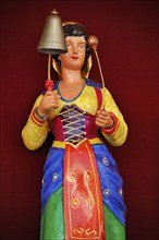 Wooden figure, colourfully painted, woman in traditional traditional costume strikes bell, bell