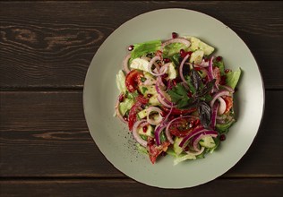 Georgian vegetable salad, tomatoes with cucumbers, red onion, walnut, pomegranate seeds, top view,