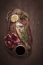 Fried dorado fish, with spices and herbs, on a wooden board, pomegranate sauce, close-up, no people