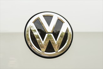 Shiny, silver Volkswagen logo, emblem with black interior on white background, golden reflection,