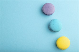 Yellow, purple and blue macaroons on blue pastel background. top view, copy space, close up, flat