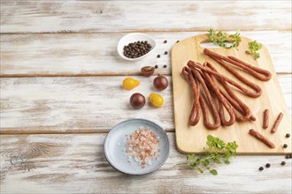 Traditional polish smoked pork sausage kabanos on cutting board with salt and pepper on white