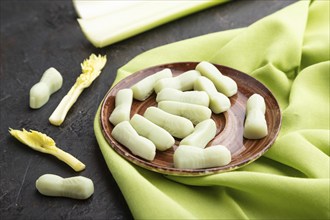 Jelly celery candies on black concrete background and green linen textile. close up, side view,