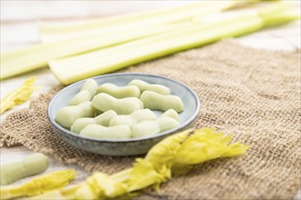 Jelly celery candies on white wooden background and linen textile. close up, side view, selective