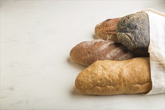 Reusable textile grocery bag with fresh baked bread on a gray concrete background. side view, copy