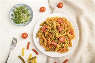 Tortiglioni semolina pasta with tomato and microgreen sprouts on a white wooden background and