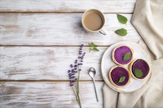 Sweet tartlets with jelly and milk cream with cup of coffee on a white wooden background and linen