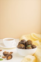 Chocolate caramel ball candies with almonds and a cup of coffee on a white and orange background