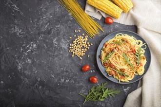 Corn noodles with tomato sauce and arugula on a black concrete background and linen textile. Top