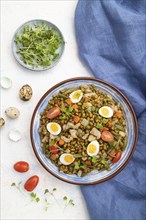 Mung bean porridge with quail eggs, tomatoes and microgreen sprouts on a white concrete background