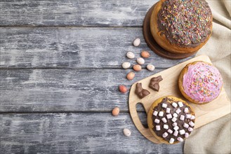 Homemade glazed and decorated easter pies with chocolate eggs and rabbits on a gray wooden