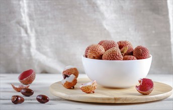 Lychee in a white plate on a white wooden background, close up