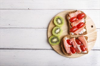 Smoked salmon sandwiches with butter and cherry tomatoes on white wooden background. top view, copy