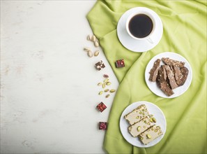 Traditional arabic sweets sesame halva with chocolate and pistachio and a cup of coffee on a white