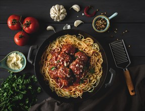 Spaghetti und Fleischbällchen in Tomatensauce, auf einem dunklen Holztisch, Gewürze, Draufsicht,