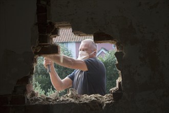 Builder removing red bricks to make window space, Suffolk, England, UK