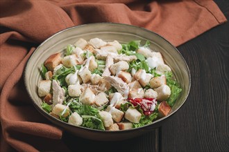 Fresh traditional Caesar salad, with chicken, on a wooden background, Top view, toned, horizontal