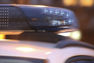 Symbolic image of a police operation: close-up of a flashing blue light on a police car