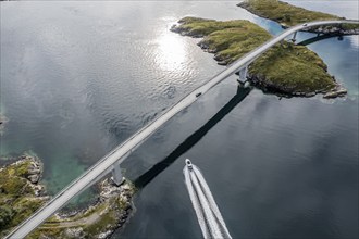 Aerial view of bridge connecting islands at the norwegian coast, motor boat below the bridge,