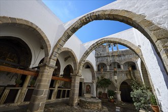 Spacious courtyard of a monastery with stone arches and medieval architecture in daylight, Inside