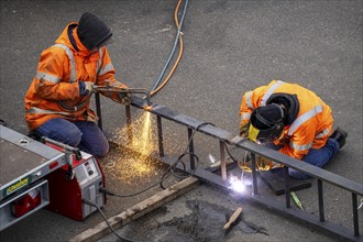 Locksmith at work, cutting and welding, on a workpiece in an industrial plant, a metal ladder is