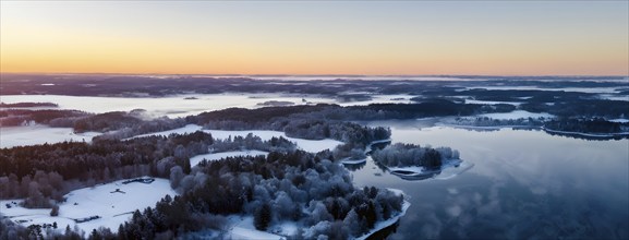 Serene winter landscape at sunrise with snow-covered trees and a frozen lake, AI generated