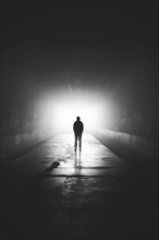 Silhouette of a man standing in a tunnel, light at the end of the tunnel, symbolic image for