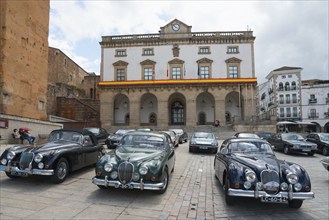 A square with a row of classic cars in front of a historic building, town hall, Ayuntamiento,