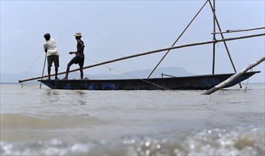 Fishermen installing a fishing net in a bamboo structure to fish in the Brahmaputra river, in