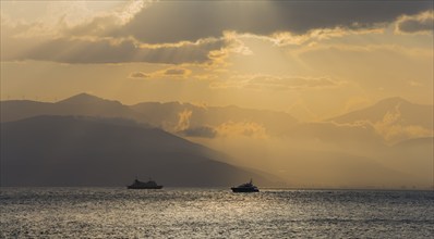 Dramatic sunset over the sea with boat silhouettes and cloudy sky, Agia Kyriaki, Nafplio, Nauplia,