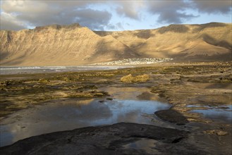 Late afternoon light on beach and cliffs La Caleta de Famara, Lanzarote, Canary islands, Spain,