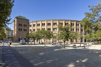 Brick bullring in a sunny setting with trees and clear skies, Granada