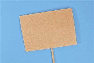 Top view of empty cardboard protest sign on blue background