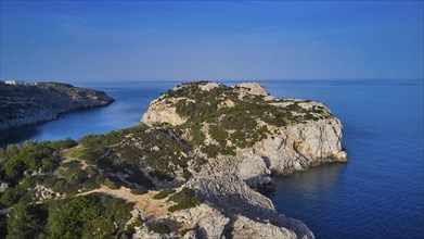 Drone shot, panorama of the rocky coast with steep cliffs, calm sea and a bright blue sky, Anthony