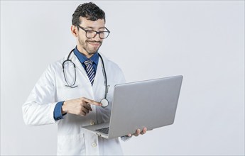 Young doctor in glasses using notebook on isolated background. Handsome doctor using laptop