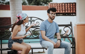 Couple sitting on a park bench arguing. A young couple arguing sitting in a park, Concept of