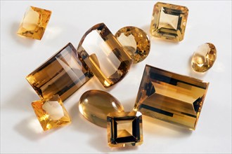 Several yellow citrine stones with different types of cutting in white background, Studio