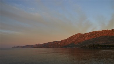 Warm morning light illuminates the mountains and the sea in a calm sea, Mani Peninsula,