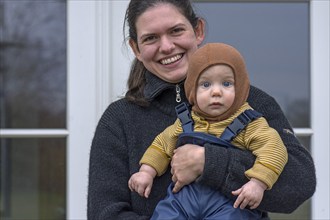 Laughing young mother with her son, 8 months, in her arms, Mecklenburg-Vorpommern, Germany, Europe