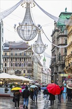 Christmas lights, passers-by with colourful umbrellas, in the Graben pedestrian zone, Vienna,