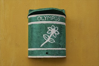 Green letterbox with floral pattern on a yellow wall, decorative and simple, Colourful mountain