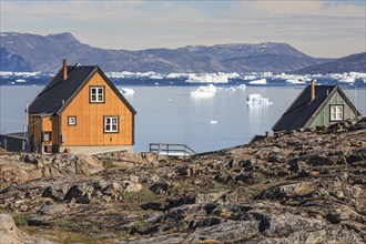 Typical Greenlandic houses in front of icebergs, Inuit settlement, summer, sunny, Uummannaq, West