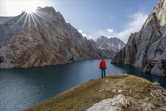 Tourist at the blue mountain lake between rocky steep mountain peaks, Sun Star, Kol Suu Lake,