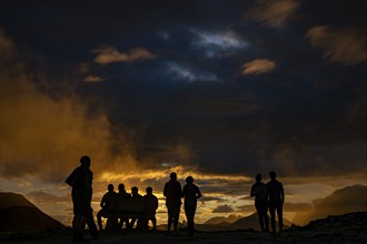 People marvelling at Montafon mountains with dramatic cloudy sky at sunset, Tschagguns, Rätikon,