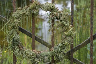 Decorative wreath, door wreath made of grass, hay tied to an iron gate, North Rhine-Westphalia,